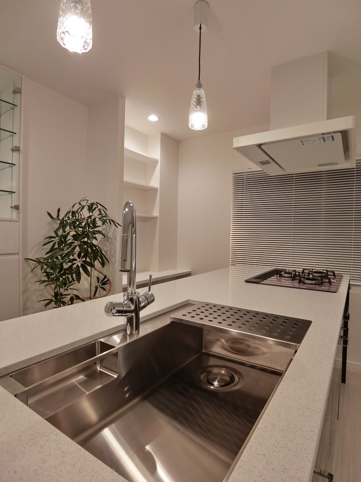 Photo of a medium sized modern galley open plan kitchen in Tokyo with a submerged sink, flat-panel cabinets, black cabinets, engineered stone countertops, grey splashback, stone slab splashback, stainless steel appliances, plywood flooring, a breakfast bar and white floors.