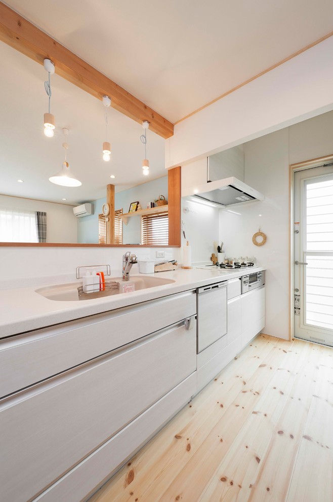 Photo of a rural open plan kitchen in Other with an integrated sink, flat-panel cabinets, white cabinets, light hardwood flooring, an island and brown floors.