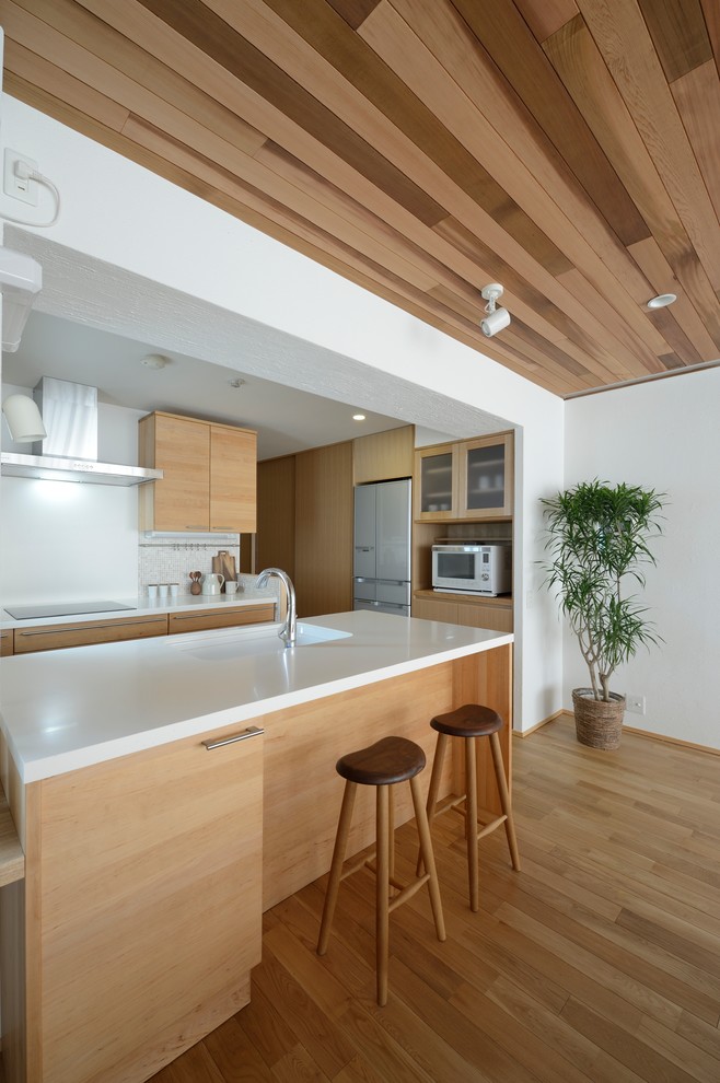 Идея дизайна: кухня в восточном стиле с плоскими фасадами, паркетным полом среднего тона и коричневым полом