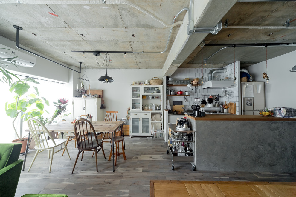 Modelo de cocina urbana pequeña abierta con suelo gris, armarios con paneles lisos, puertas de armario blancas, encimera de madera, salpicadero blanco, electrodomésticos de acero inoxidable, suelo de madera en tonos medios, península y encimeras marrones