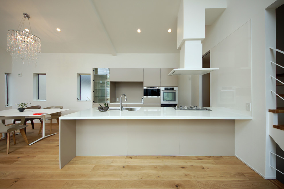 На фото: прямая кухня-гостиная в стиле модернизм с одинарной мойкой, плоскими фасадами, светлым паркетным полом, полуостровом и бежевым полом с