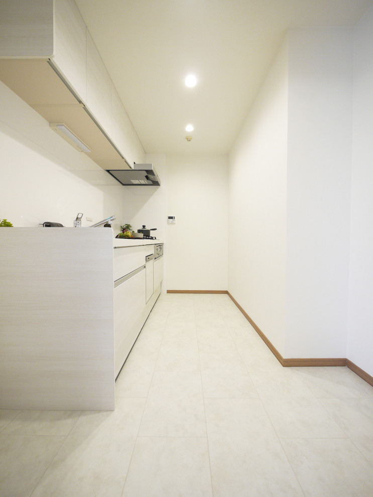 На фото: отдельная, прямая кухня в стиле модернизм с светлыми деревянными фасадами, полом из керамической плитки, островом, белым полом, белой столешницей и потолком с обоями