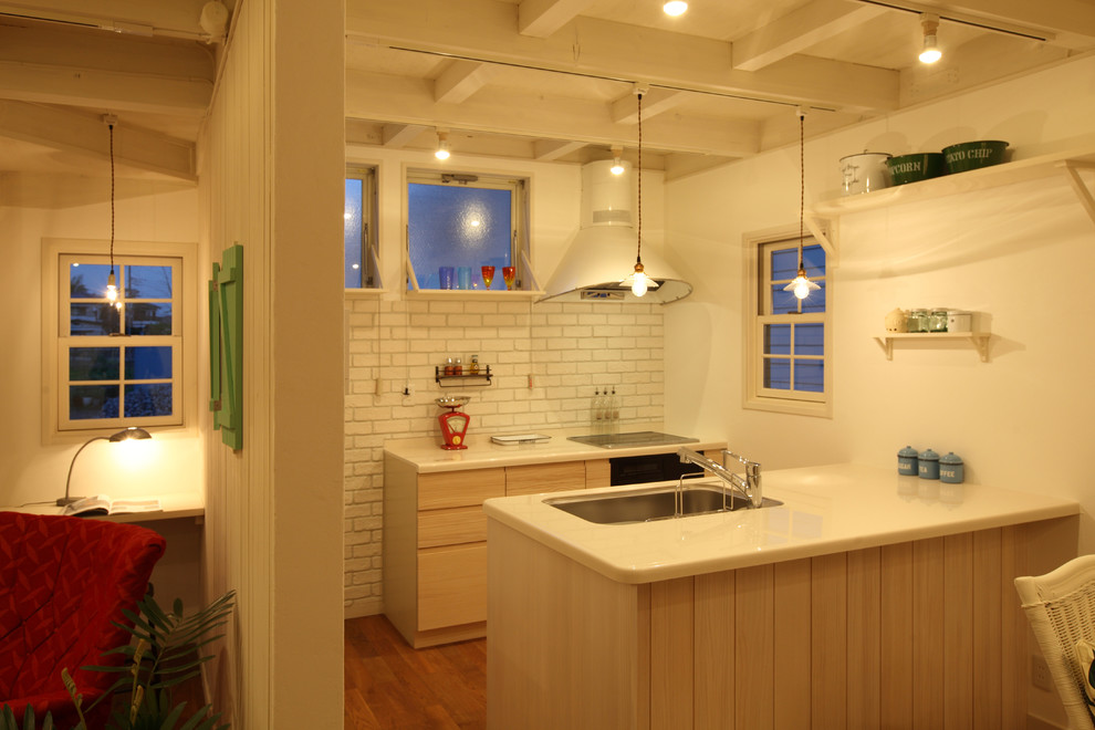 Esempio di un piccolo cucina con isola centrale stile marinaro con lavello a vasca singola, ante lisce, ante in legno chiaro, pavimento in legno massello medio e pavimento marrone