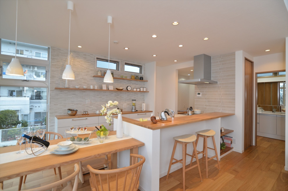 Exempel på ett mellanstort nordiskt brun linjärt brunt kök med öppen planlösning, med en enkel diskho, vita skåp, bänkskiva i koppar, vitt stänkskydd, rostfria vitvaror, mellanmörkt trägolv och brunt golv