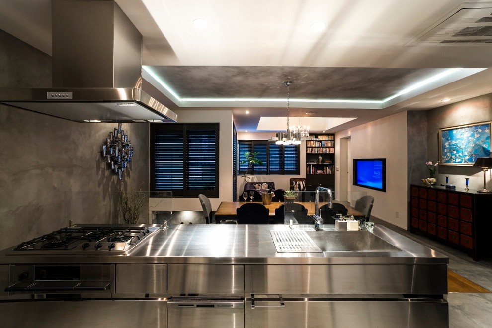 Exemple d'une cuisine ouverte linéaire tendance en inox avec un évier 1 bac, un placard à porte plane, un plan de travail en inox, îlot et un sol gris.