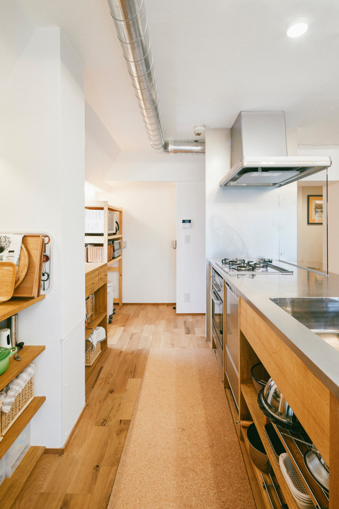 名古屋にある広いインダストリアルスタイルのおしゃれなII型キッチン (一体型シンク、フラットパネル扉のキャビネット、中間色木目調キャビネット、ステンレスカウンター、シルバーの調理設備、無垢フローリング、アイランドなし、茶色い床) の写真
