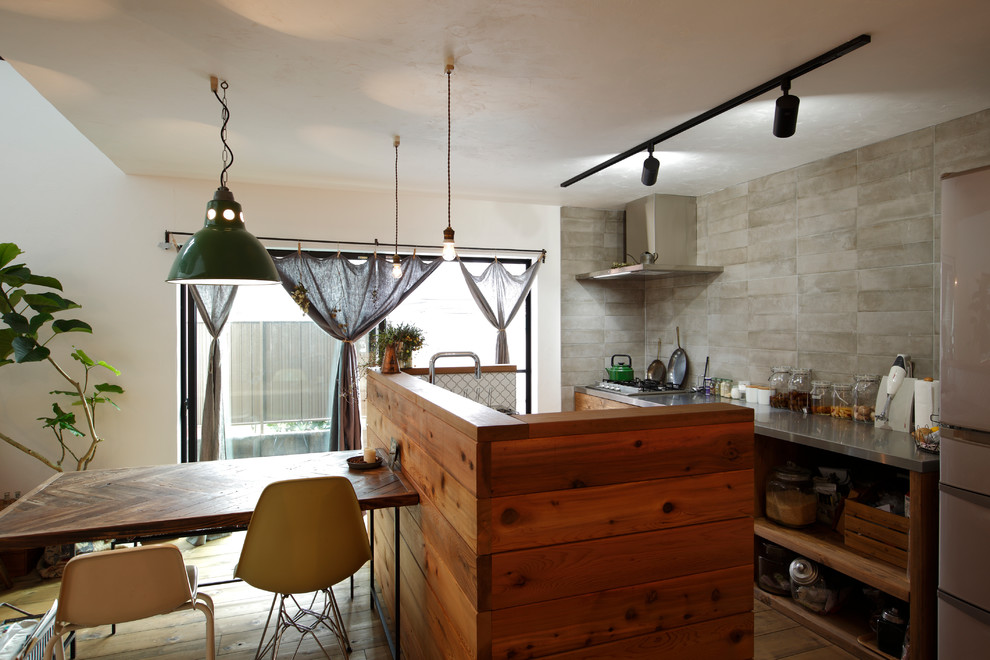 他の地域にあるコンテンポラリースタイルのおしゃれなキッチン (オープンシェルフ、ステンレスカウンター、グレーのキッチンパネル、無垢フローリング、茶色い床) の写真