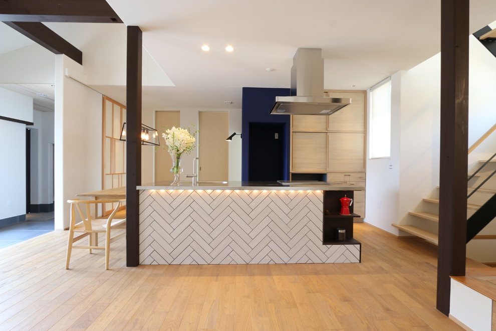 Diseño de cocina lineal escandinava abierta con encimera de acero inoxidable, electrodomésticos de acero inoxidable, suelo de madera clara, una isla y suelo beige