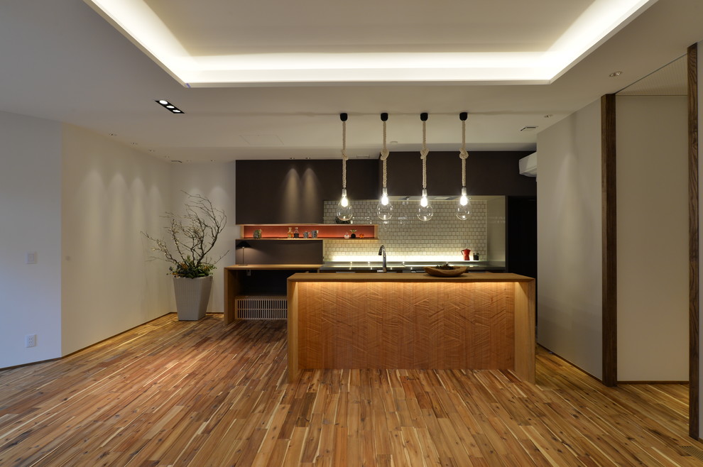 Imagen de cocina de estilo zen con suelo de madera en tonos medios, una isla y suelo marrón