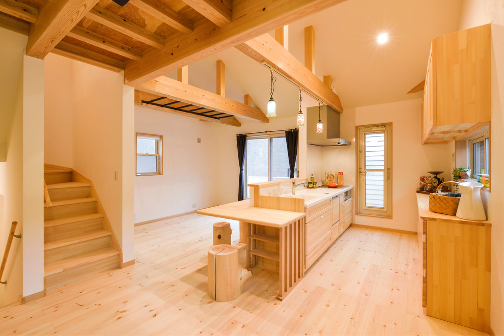 Foto på ett lantligt kök, med en integrerad diskho, släta luckor, skåp i mellenmörkt trä, ljust trägolv, en köksö och brunt golv