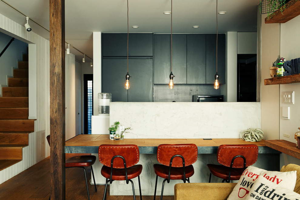 Imagen de cocina contemporánea abierta con armarios con paneles lisos, puertas de armario negras, encimera de madera, salpicadero negro, suelo de madera oscura y península