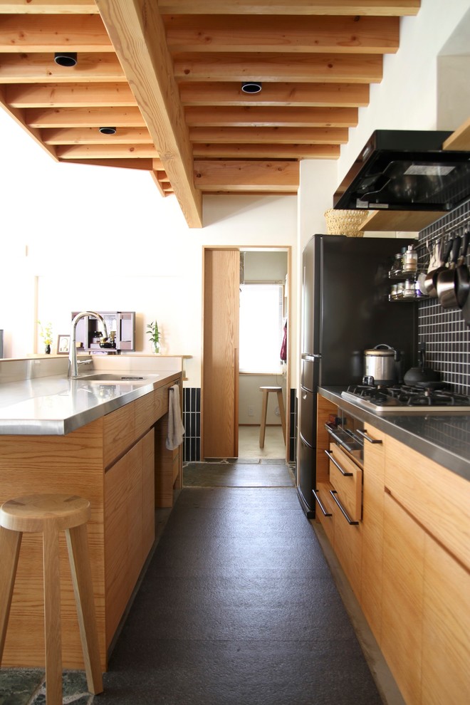 Foto på ett funkis kök, med släta luckor, skåp i mellenmörkt trä, bänkskiva i rostfritt stål, svart stänkskydd, stänkskydd i mosaik, rostfria vitvaror, en köksö och grått golv