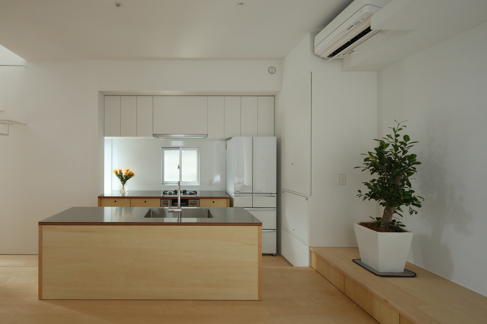 Esempio di una cucina moderna con lavello integrato, ante lisce, top in acciaio inossidabile, paraspruzzi bianco, elettrodomestici in acciaio inossidabile e parquet chiaro