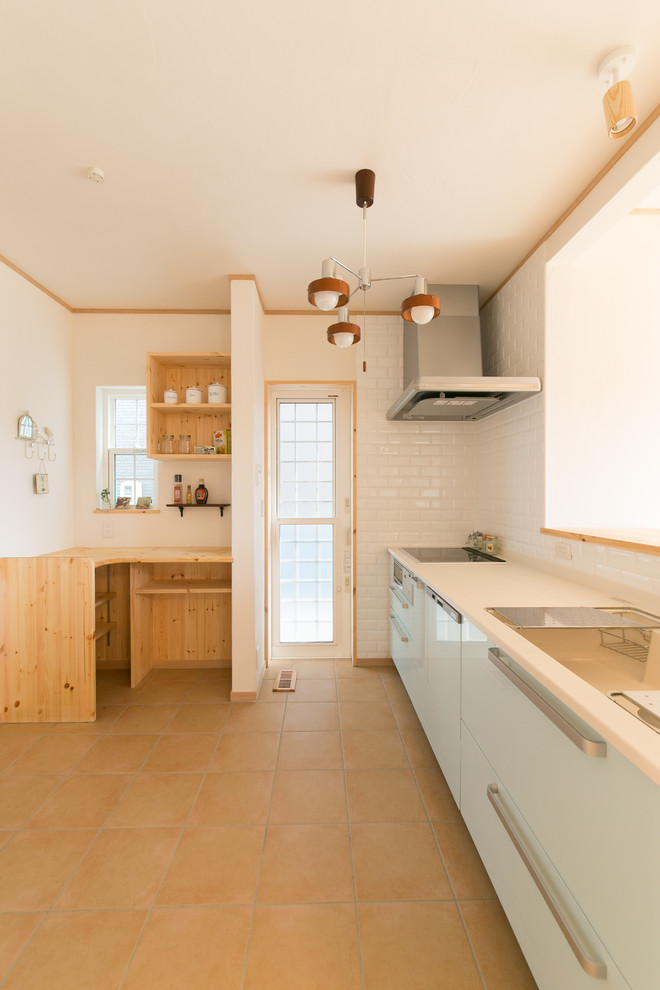 Modelo de cocina lineal de estilo zen con fregadero integrado, armarios con paneles lisos, suelo de baldosas de terracota, península, suelo marrón y encimeras blancas