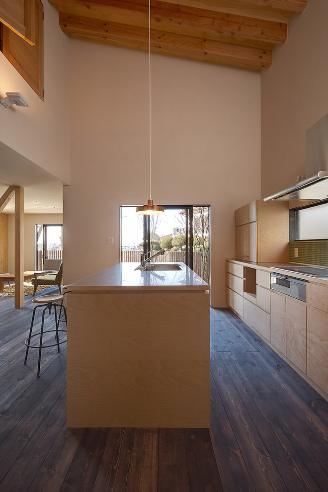 Exemple d'une cuisine ouverte parallèle scandinave en bois clair avec un évier 1 bac, un placard à porte plane, une crédence verte, parquet foncé, îlot et un sol marron.