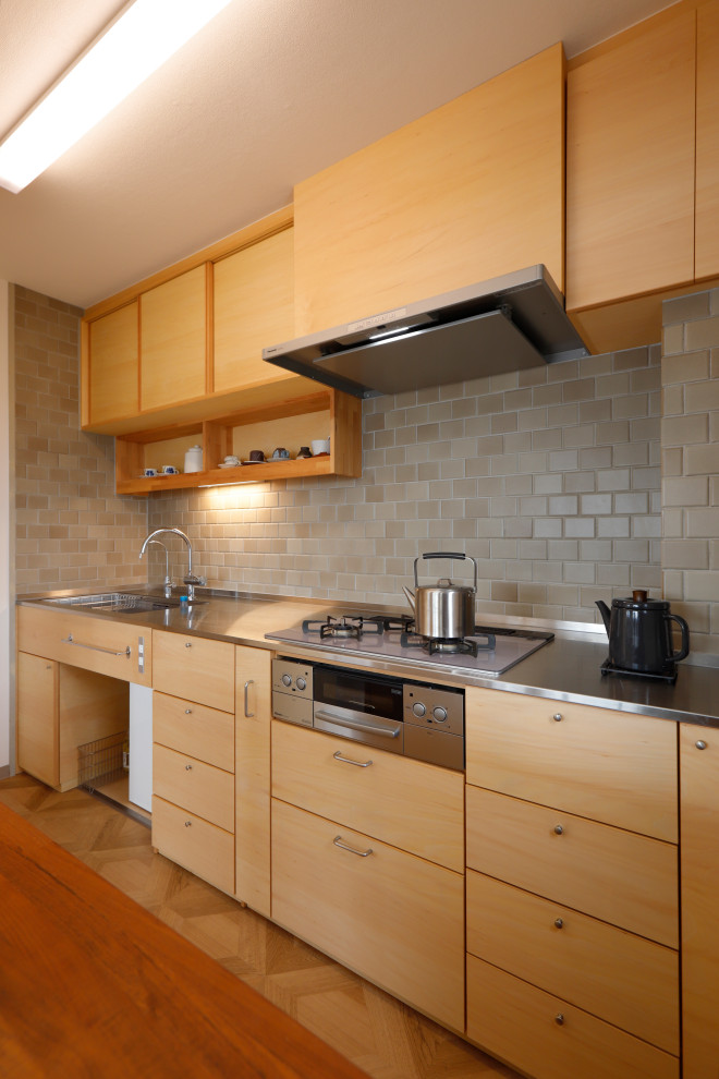 Exempel på ett skandinaviskt beige linjärt beige kök och matrum, med en integrerad diskho, skåp i ljust trä, bänkskiva i rostfritt stål, rostfria vitvaror, en köksö och beiget golv