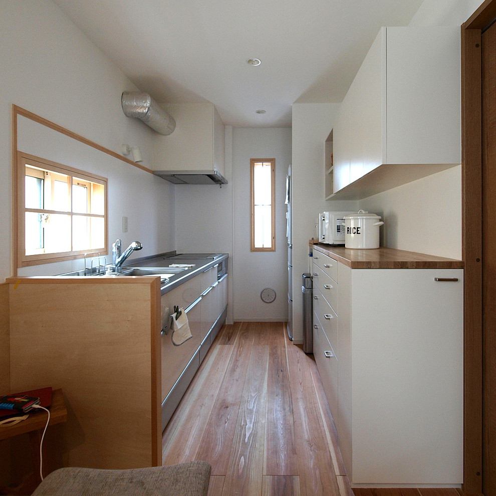 This is an example of a scandi single-wall kitchen in Tokyo with white splashback, light hardwood flooring and beige floors.