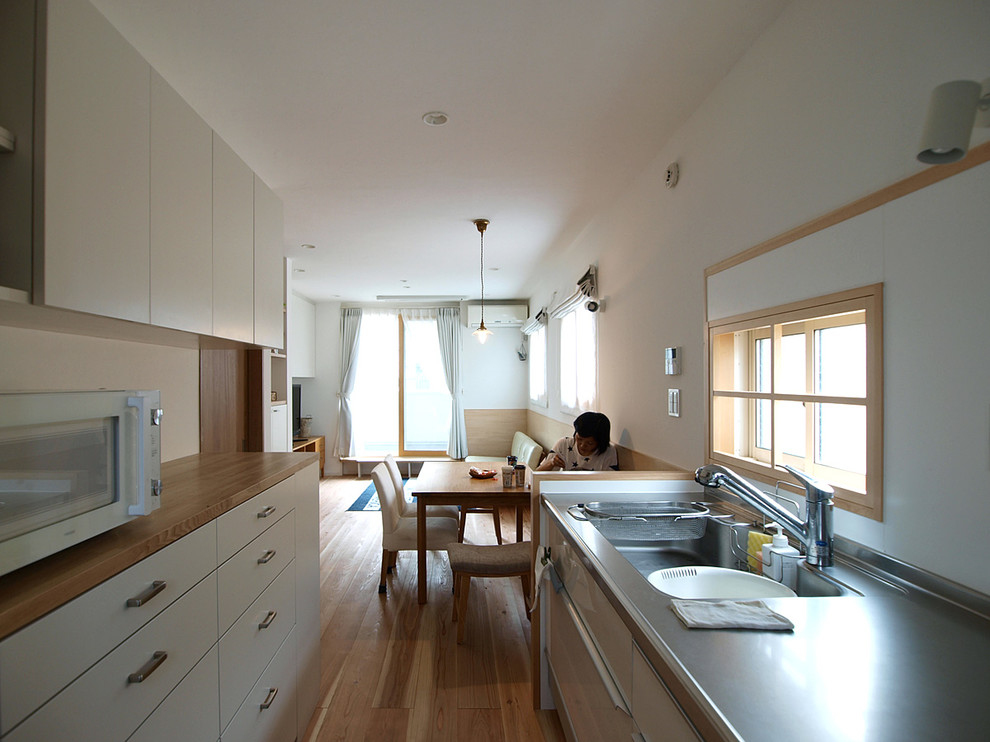 東京23区にある北欧スタイルのおしゃれなI型キッチン (白いキッチンパネル、淡色無垢フローリング、ベージュの床) の写真