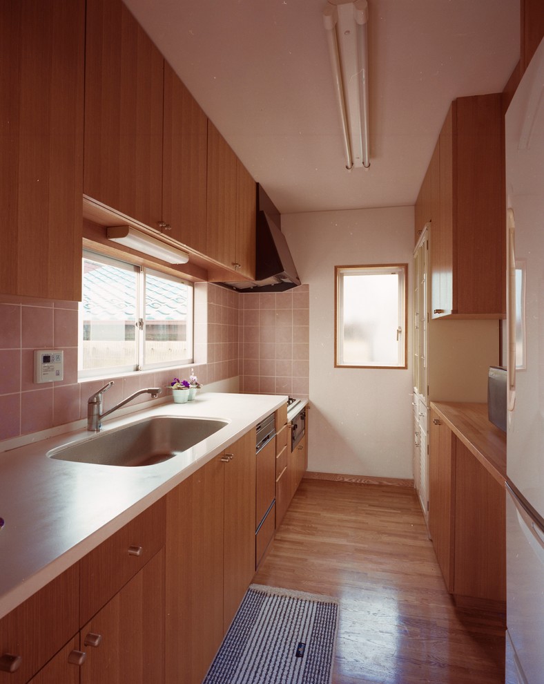 Idéer för avskilda, mellanstora funkis linjära vitt kök, med en undermonterad diskho, luckor med profilerade fronter, bruna skåp, bänkskiva i koppar, rosa stänkskydd, stänkskydd i keramik, integrerade vitvaror, mellanmörkt trägolv och brunt golv