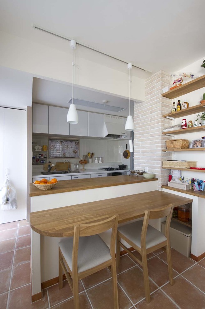 Idéer för att renovera ett litet lantligt kök, med en undermonterad diskho, vitt stänkskydd, klinkergolv i terrakotta och en halv köksö