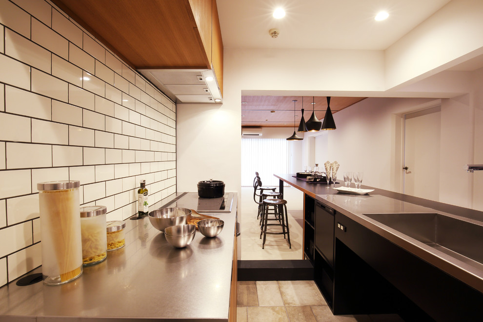 他の地域にあるコンテンポラリースタイルのおしゃれなキッチン (シングルシンク、フラットパネル扉のキャビネット、中間色木目調キャビネット、ステンレスカウンター、白いキッチンパネル) の写真