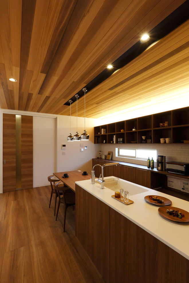 Idées déco pour une cuisine parallèle asiatique en bois brun avec un évier intégré, un placard à porte plane, une crédence blanche, un sol en bois brun et un sol marron.