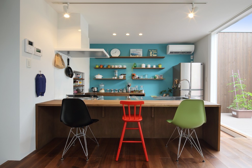 Open concept kitchen - eclectic single-wall medium tone wood floor and brown floor open concept kitchen idea in Other with stainless steel countertops, an integrated sink and a peninsula