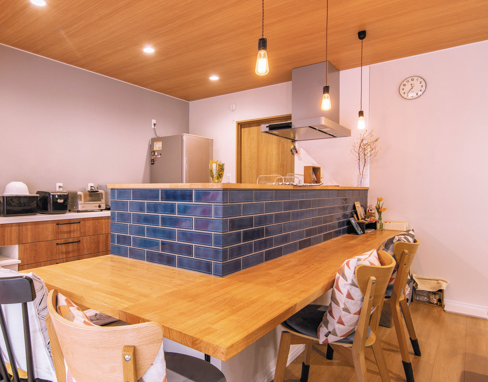 Exempel på ett skandinaviskt blå linjärt blått kök med öppen planlösning, med mellanmörkt trägolv, brunt golv, släta luckor och en halv köksö