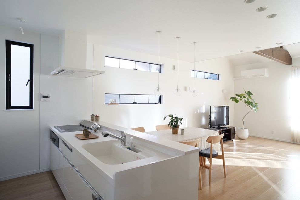 Идея дизайна: прямая кухня-гостиная в стиле модернизм с монолитной мойкой, плоскими фасадами, белыми фасадами, светлым паркетным полом, полуостровом, бежевым полом и белой столешницей