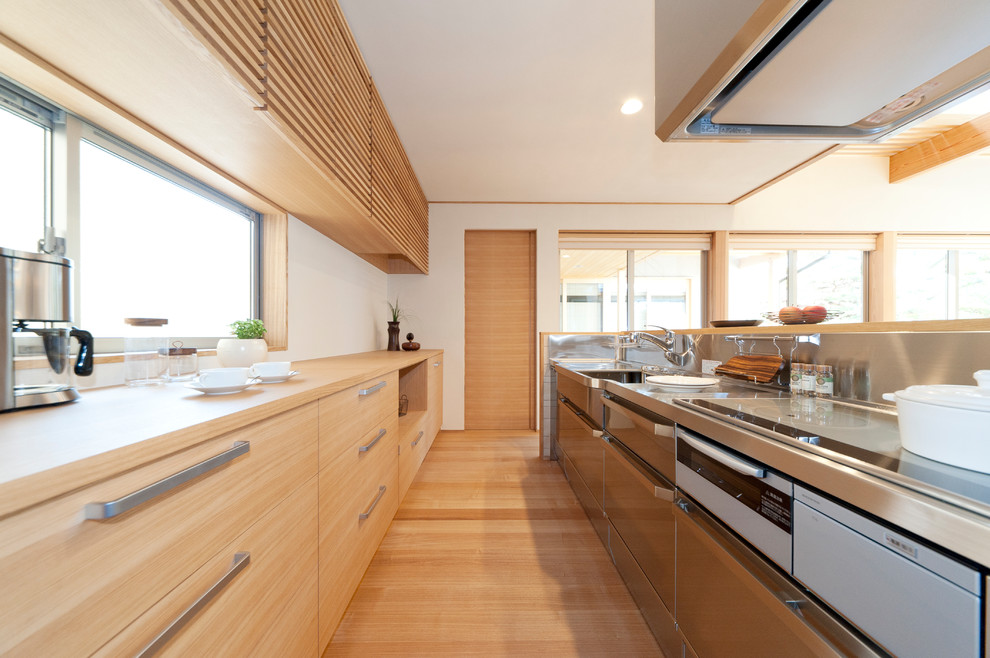 Идея дизайна: прямая кухня-гостиная в стиле модернизм с столешницей из нержавеющей стали, светлым паркетным полом, островом, бежевым полом и бежевой столешницей