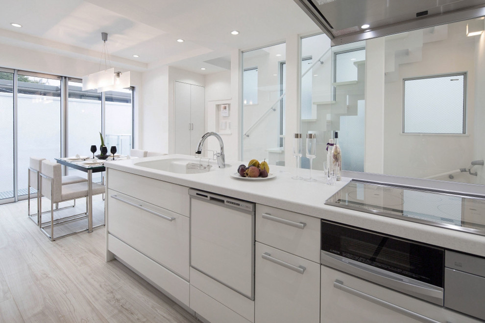 Idéer för att renovera ett mellanstort funkis linjärt kök och matrum, med en integrerad diskho, vita skåp, släta luckor, glaspanel som stänkskydd, vita vitvaror, ljust trägolv och en halv köksö