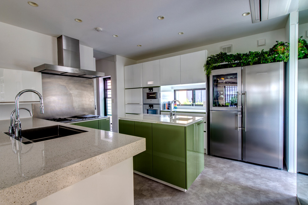 Diseño de cocinas en L moderna grande abierta con fregadero bajoencimera, armarios con paneles lisos, puertas de armario verdes, encimera de terrazo, electrodomésticos blancos y una isla
