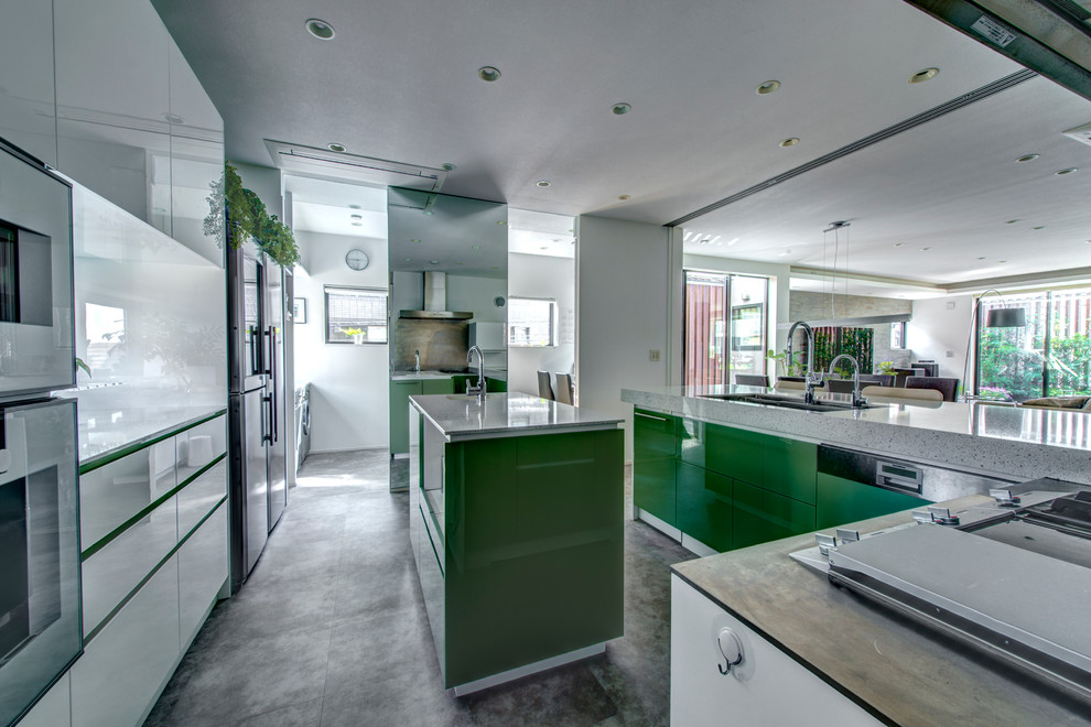 Ejemplo de cocinas en L moderna grande abierta con fregadero bajoencimera, armarios con paneles lisos, puertas de armario verdes, encimera de terrazo, electrodomésticos blancos y una isla