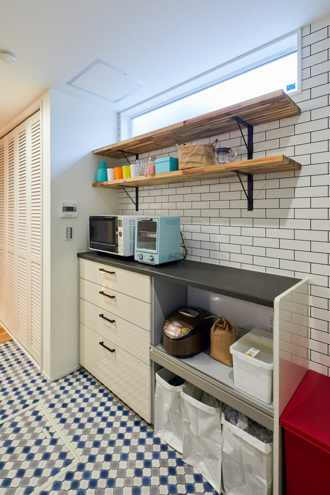 Imagen de cocina costera con puertas de armario blancas, electrodomésticos blancos, suelo turquesa y encimeras negras