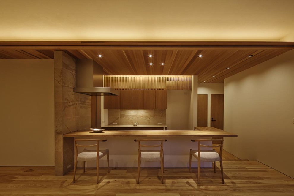 Offene, Zweizeilige Asiatische Küche mit flächenbündigen Schrankfronten, hellbraunen Holzschränken, Arbeitsplatte aus Holz, Küchenrückwand in Beige, braunem Holzboden, Halbinsel und braunem Boden in Kyoto