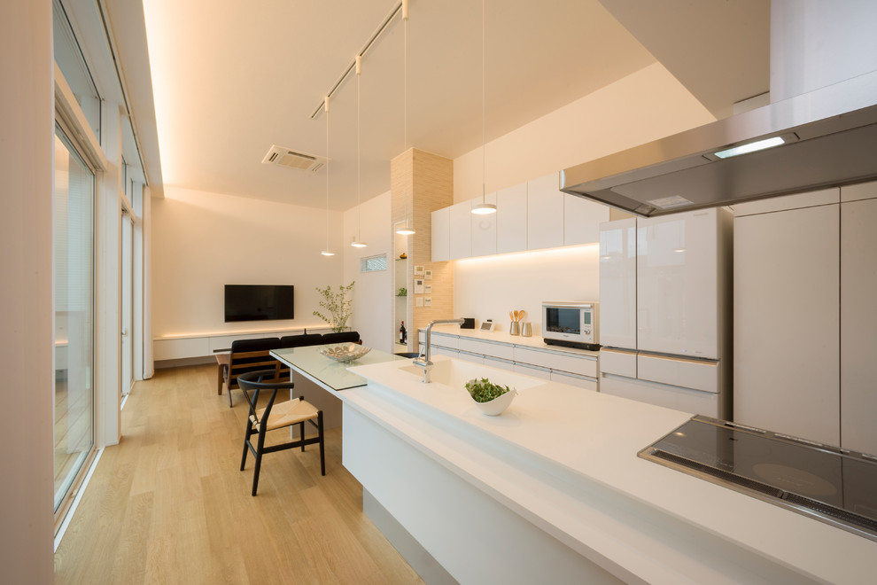 Offene, Einzeilige Moderne Küche mit integriertem Waschbecken, flächenbündigen Schrankfronten, weißen Schränken, hellem Holzboden, Kücheninsel und braunem Boden in Sonstige