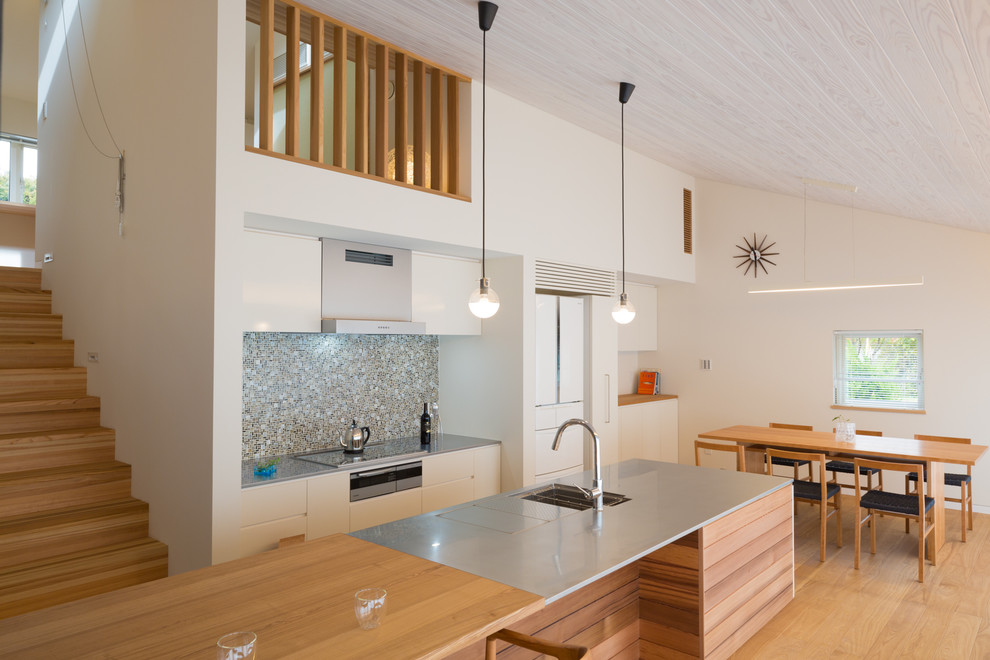 Exempel på ett modernt kök och matrum, med bänkskiva i rostfritt stål, ljust trägolv, släta luckor, vita skåp, flerfärgad stänkskydd, stänkskydd i glaskakel och rostfria vitvaror