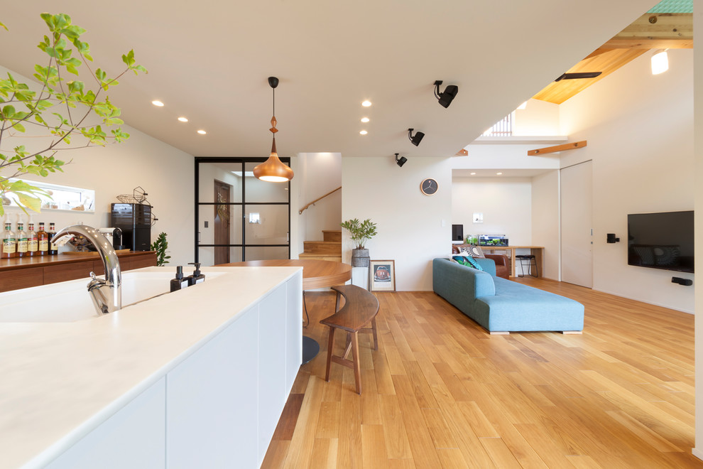 Contemporary open plan kitchen in Other with brown floors, white worktops, an integrated sink and medium hardwood flooring.