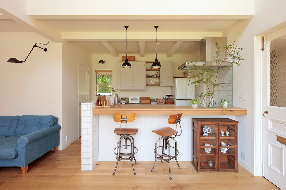 Offene, Zweizeilige Skandinavische Küche mit Arbeitsplatte aus Holz, Küchenrückwand in Weiß, hellem Holzboden, Halbinsel und braunem Boden in Yokohama