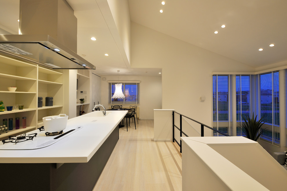 На фото: прямая кухня-гостиная в современном стиле с монолитной мойкой, черными фасадами, деревянным полом, островом и бежевым полом
