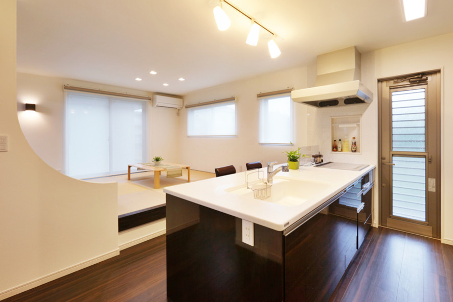 Immagine di una cucina moderna di medie dimensioni con ante in legno bruno, top in superficie solida, paraspruzzi bianco, pavimento in compensato, penisola, pavimento marrone e top bianco