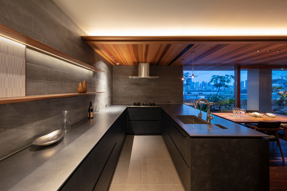Источник вдохновения для домашнего уюта: угловая кухня-гостиная в стиле модернизм с одинарной мойкой, плоскими фасадами, черными фасадами, столешницей из нержавеющей стали, полуостровом и серым полом