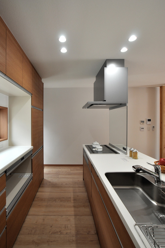 Foto på ett mellanstort funkis linjärt kök med öppen planlösning, med en integrerad diskho, släta luckor, skåp i ljust trä, bänkskiva i koppar, plywoodgolv och en köksö