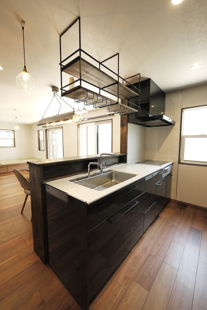 Foto på ett orientaliskt vit linjärt kök med öppen planlösning, med en undermonterad diskho, släta luckor, svarta skåp, bänkskiva i koppar, vitt stänkskydd, glaspanel som stänkskydd, rostfria vitvaror, plywoodgolv, en halv köksö och brunt golv