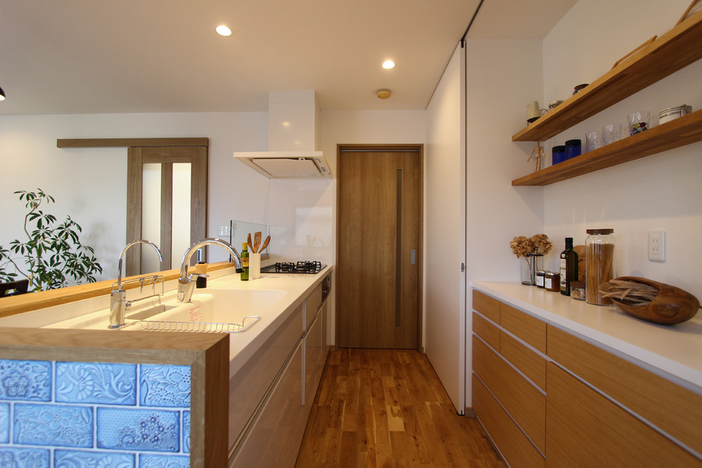 Modelo de cocina lineal escandinava de tamaño medio abierta con fregadero integrado, armarios con paneles lisos, puertas de armario de madera oscura, salpicadero blanco, suelo de madera en tonos medios y suelo marrón