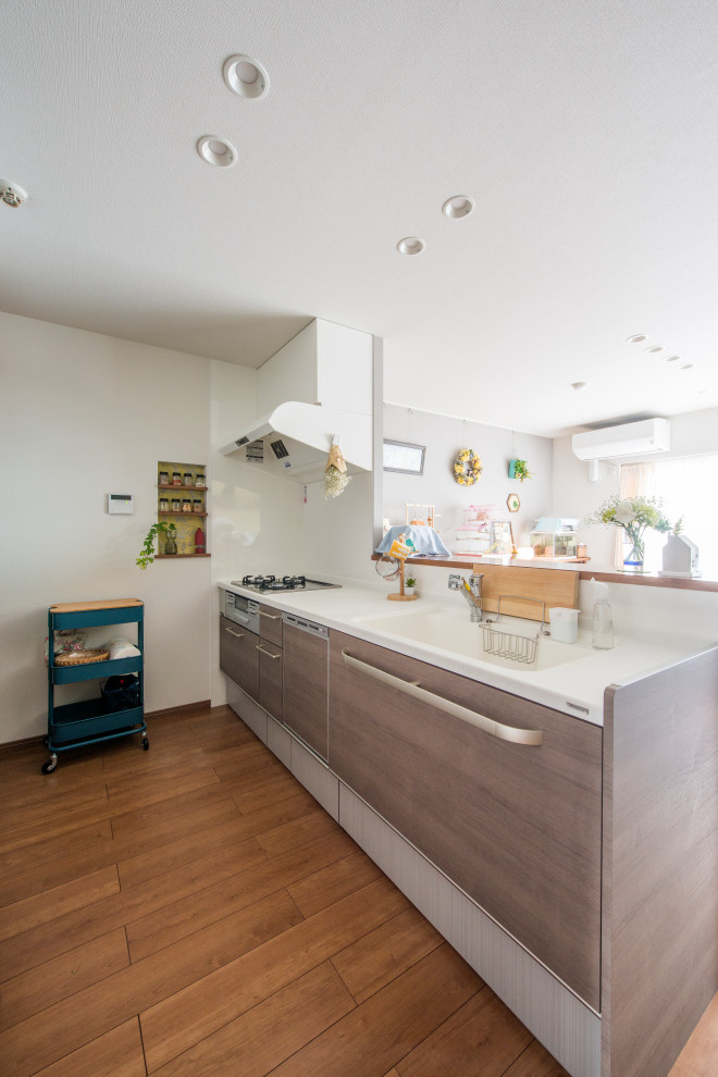 Cette image montre une cuisine ouverte bohème de taille moyenne avec un plan de travail en surface solide, un électroménager en acier inoxydable, un sol en contreplaqué et un plan de travail blanc.