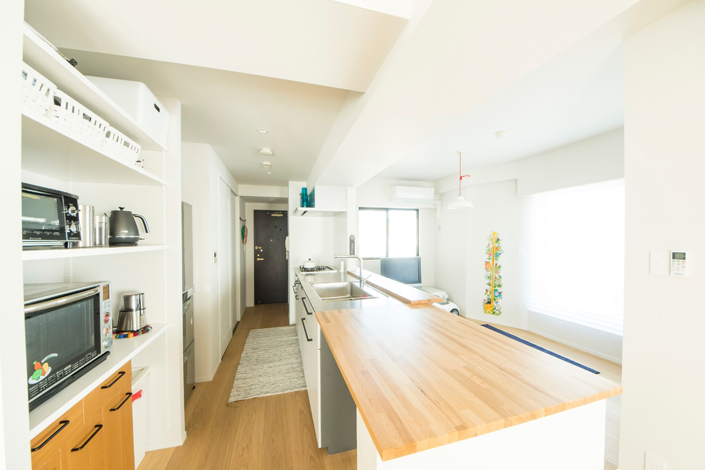 福岡にある小さな北欧スタイルのおしゃれなキッチン (一体型シンク、フラットパネル扉のキャビネット、白いキャビネット、ステンレスカウンター、無垢フローリング、茶色い床、ベージュのキッチンカウンター) の写真