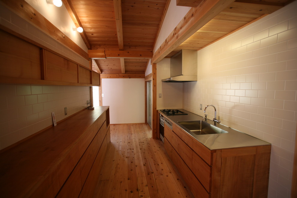 Exemple d'une cuisine linéaire asiatique fermée et de taille moyenne avec un évier intégré, des portes de placard marrons, un plan de travail en inox, une crédence marron, une crédence en bois, un sol en bois brun et un sol marron.