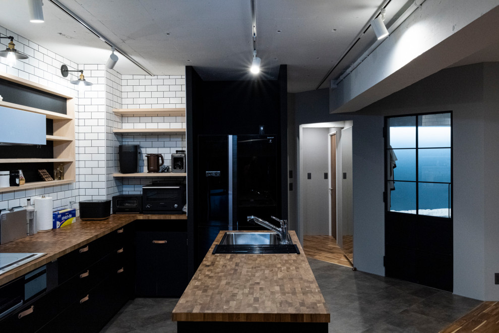 Ejemplo de cocinas en L urbana de tamaño medio abierta con fregadero integrado, salpicadero negro, electrodomésticos negros, una isla, suelo gris y encimeras marrones