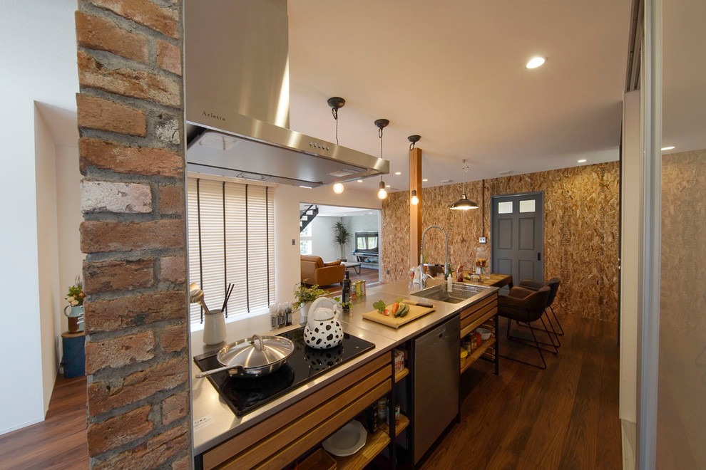 他の地域にあるインダストリアルスタイルのおしゃれなキッチン (シングルシンク、中間色木目調キャビネット、ステンレスカウンター、無垢フローリング、茶色い床) の写真
